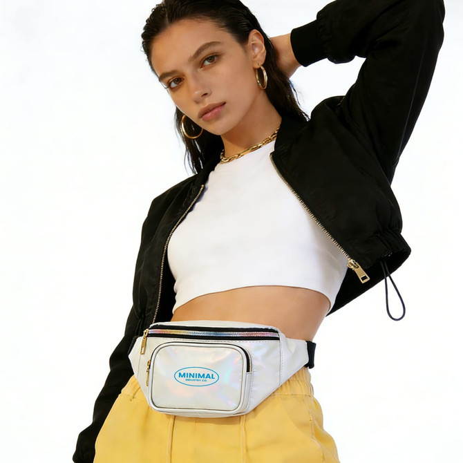 A model poses with a holographic bum bag featuring a logo, styled with a black jacket and yellow trousers.