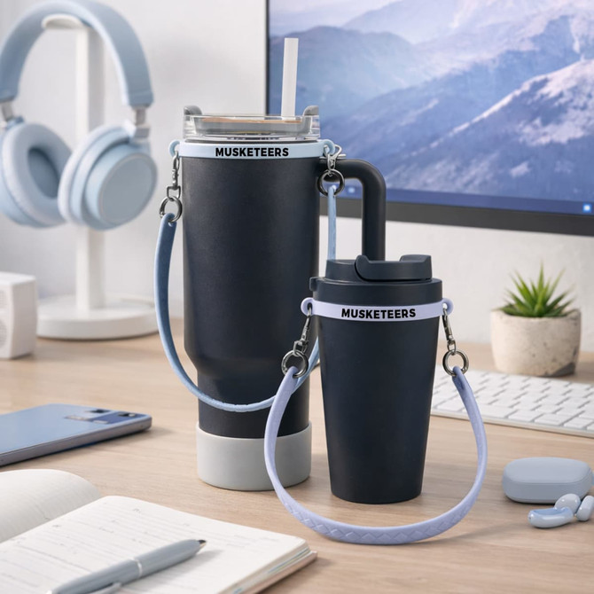 A drink bottle carrying two silicone cup carry straps in black and light blue, placed on a desk with headphones and stationery.