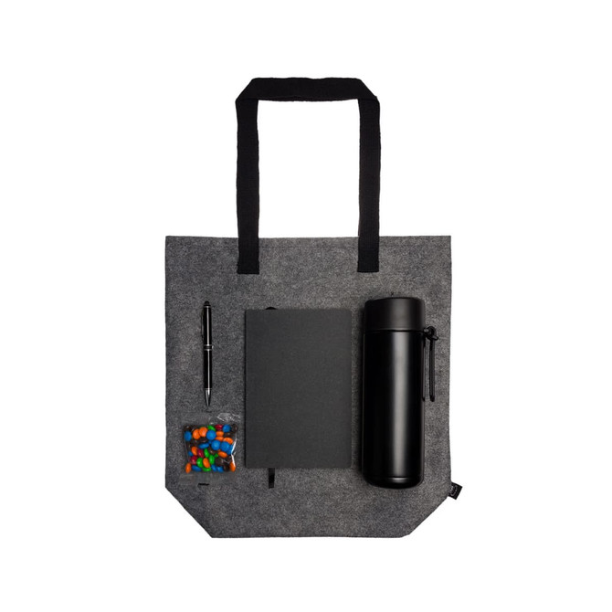 A gray tote bag contains a black drink bottle, a black notebook, a pen, and a bag of colorful candies.