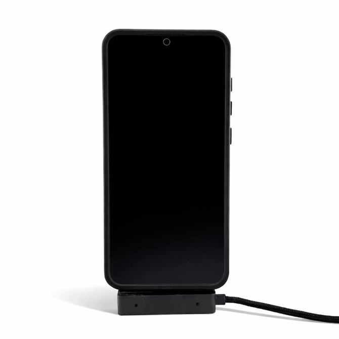 A black phone is displayed on a charger, connected by a charging cable. The charger has a sleek design.
