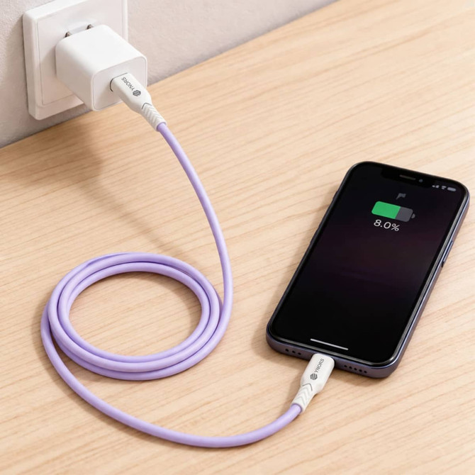 A purple 100W fast charging cable connected to a wall charger and an iPhone on a wooden surface.