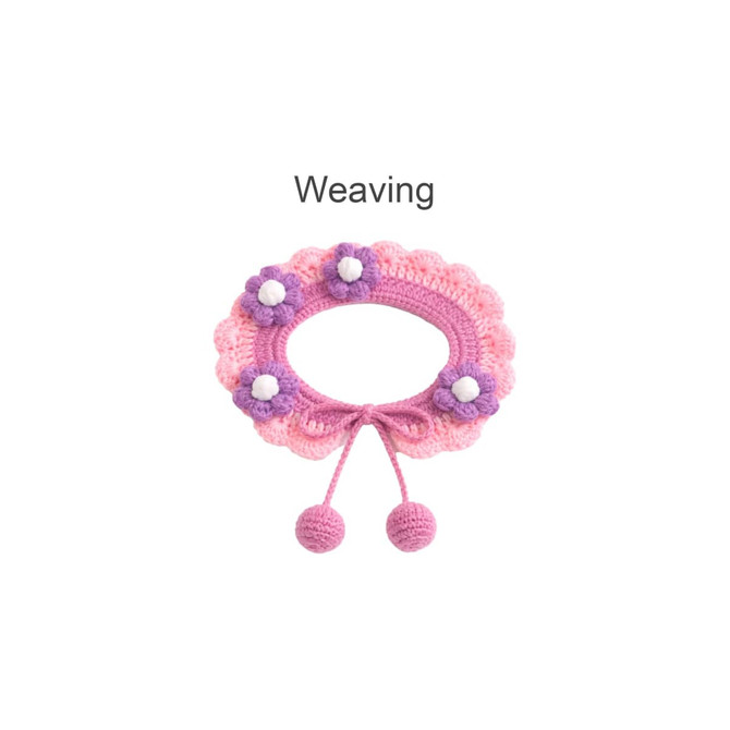 A pink crochet pet bib features scalloped edges, purple and white flower embellishments, and tied ends with pom-poms.