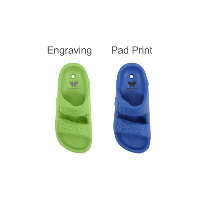 A green and a blue clog shoe charm displayed side by side, featuring a logo and various decoration options.