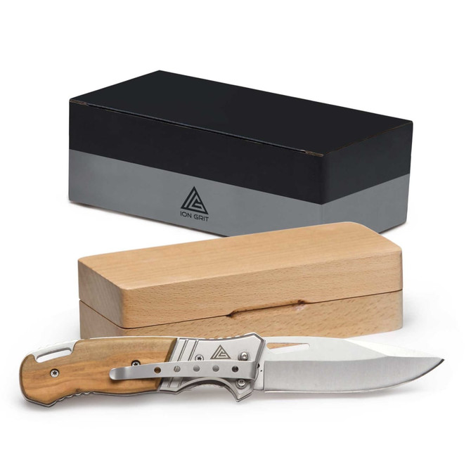 A stainless steel pocket knife with a wooden handle, displayed next to a sleek black and natural wooden box.