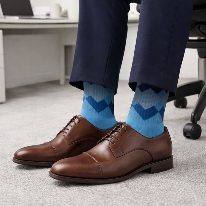 Brown dress shoes paired with blue patterned woven socks, worn with navy trousers in an office setting.