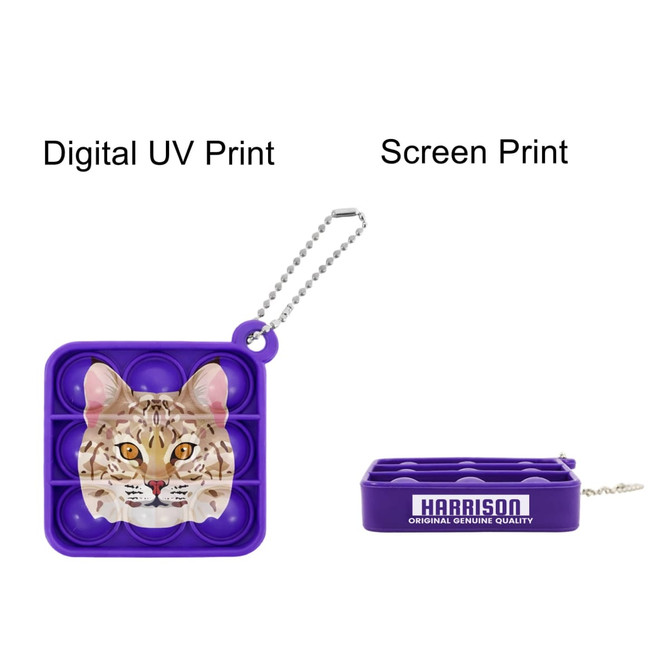 A purple square fidget keychain featuring a cat design, with a chain for attachment and branding visible.