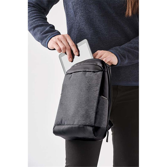 A person inserting a tablet into a grey and black Quito Sling Backpack with a sleek design and branding.