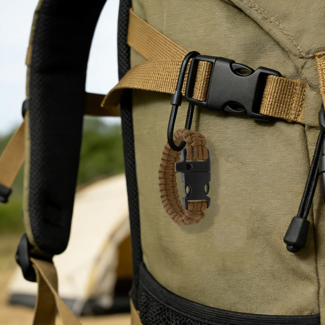 A brown paracord bracelet with a whistle attached to a tactical backpack strap in an outdoor setting.