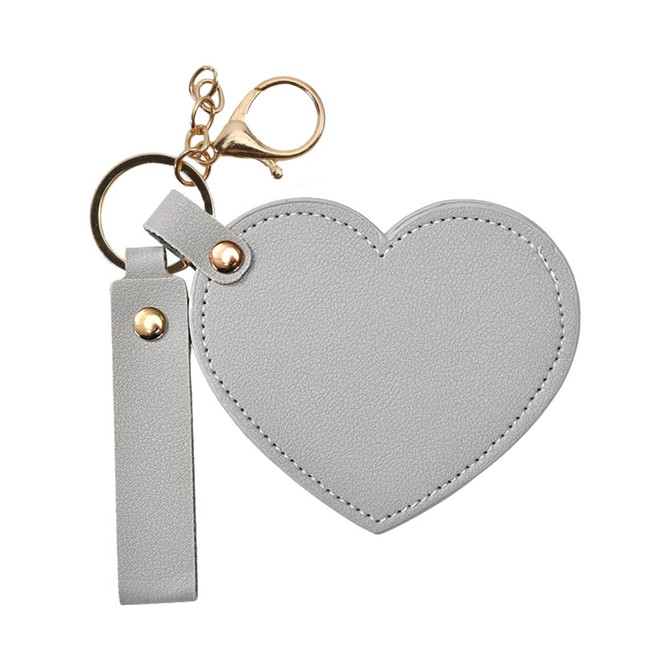 A heart-shaped compact mirror in grey with a keychain attachment and a gold clasp.