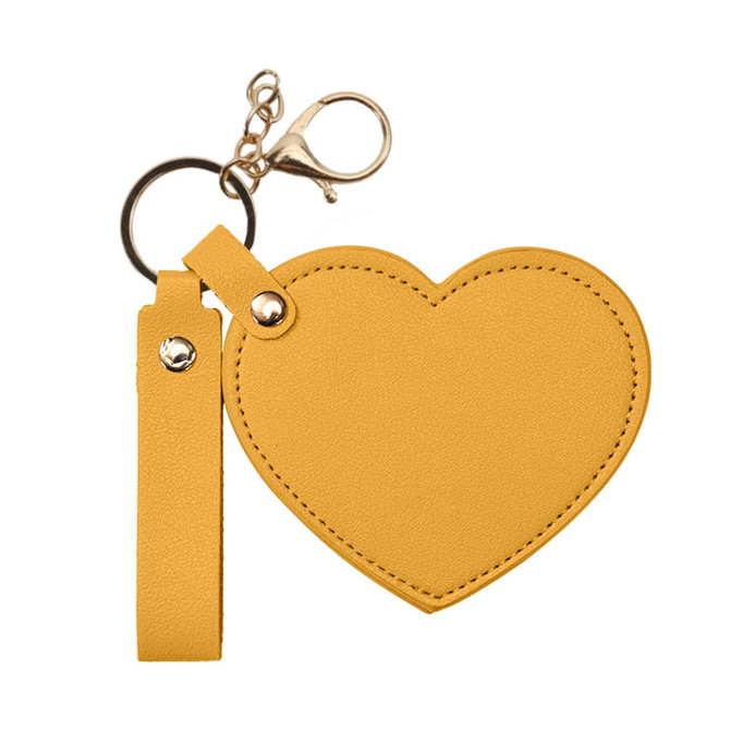 A heart-shaped compact mirror in bright yellow, attached to a keychain with a clip and strap.