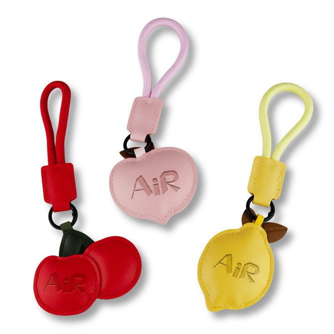 Three bag charms in red, pink, and yellow, featuring apple and lemon shapes with one charm having a logo.