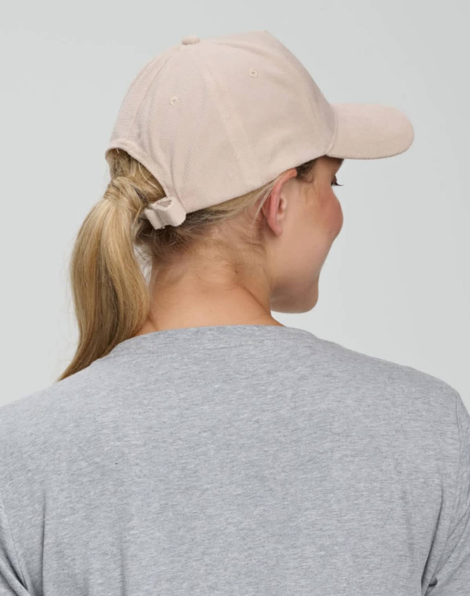 A beige Jacquard Texture 5 Panel Cap with a back ponytail opening, worn by a person with long hair.