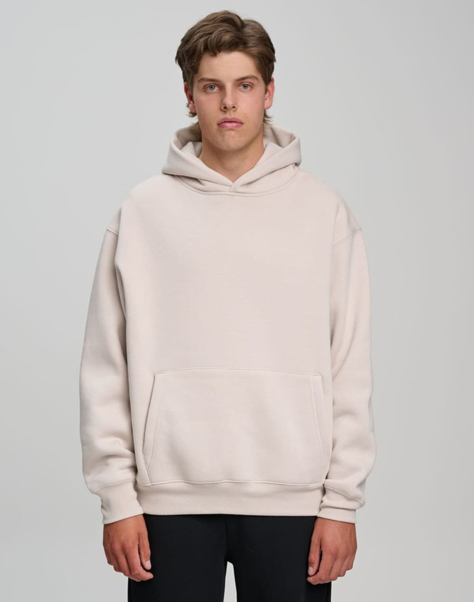 A model wearing a unisex premium fleece oversized hoodie in a light beige colour, featuring a front pocket and a hood.