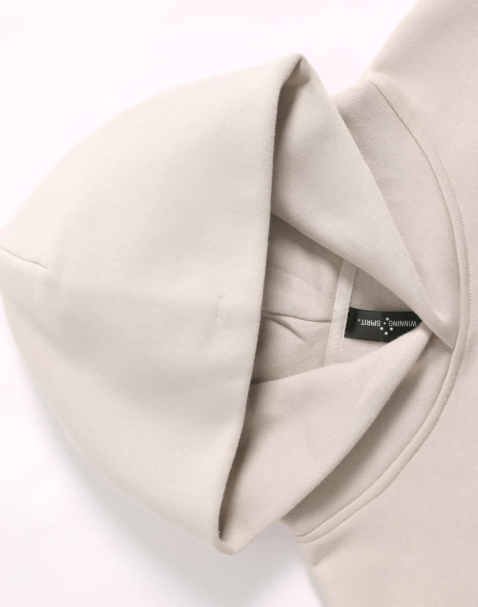 A premium fleece oversized hoodie in light beige with an attached hood and a logo label inside.