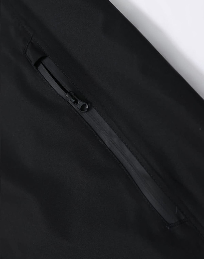 A black waterproof jacket featuring a zippered pocket and a smooth fabric texture. It has a logo on the jacket.
