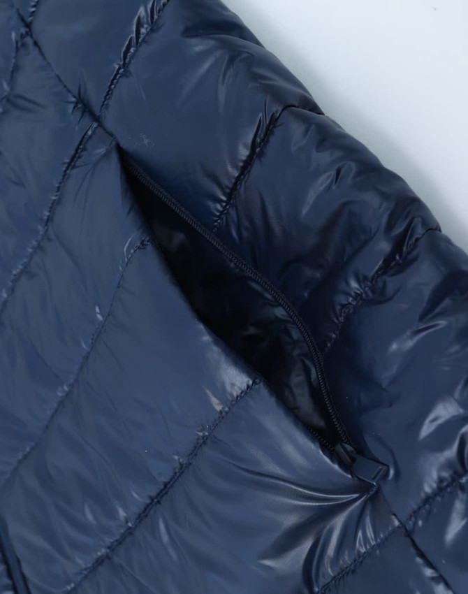 A navy blue lightweight hooded puffer jacket with a zippered pocket detail. It has a sleek, shiny finish and includes a logo.