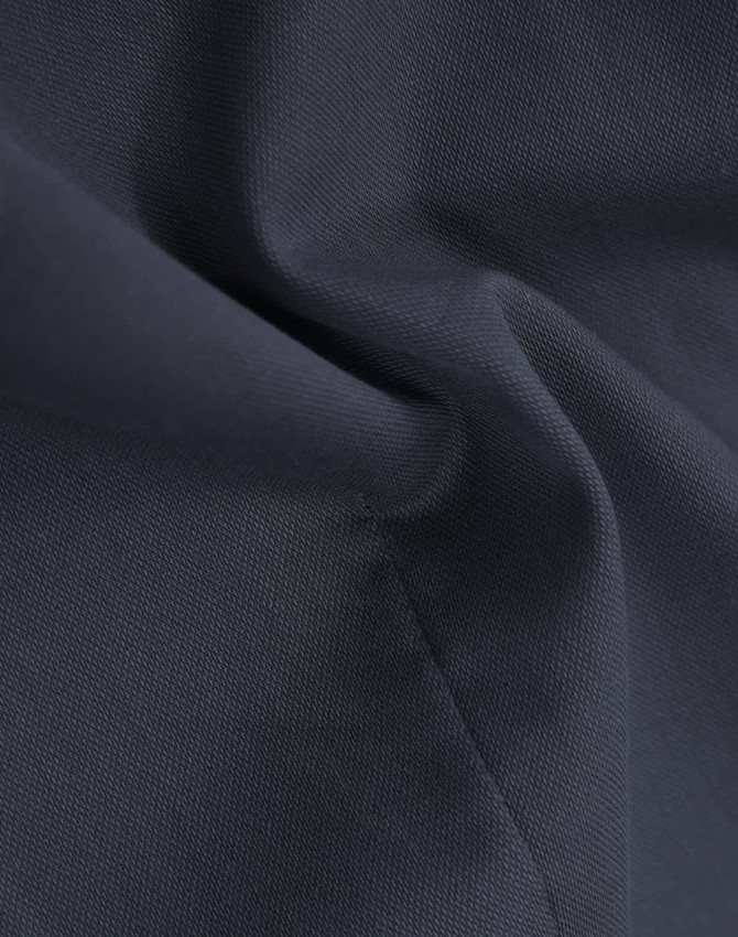 A close-up of navy cotton blend fabric, highlighting a textured weave with subtle folds.