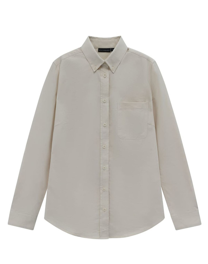 A beige long-sleeve shirt with a collar and a chest pocket, featuring a logo on the tag.