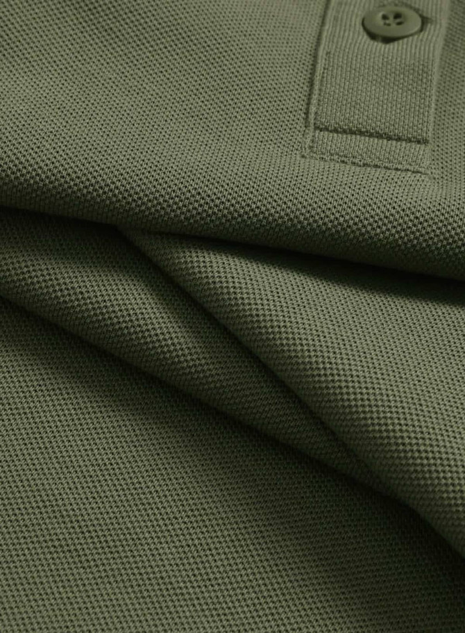A close-up of an olive green ultrafine cotton pique polo shirt featuring a button and textured fabric.