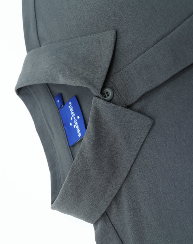 A grey men's polo featuring a collar and a button closure, displaying a tag with a logo.