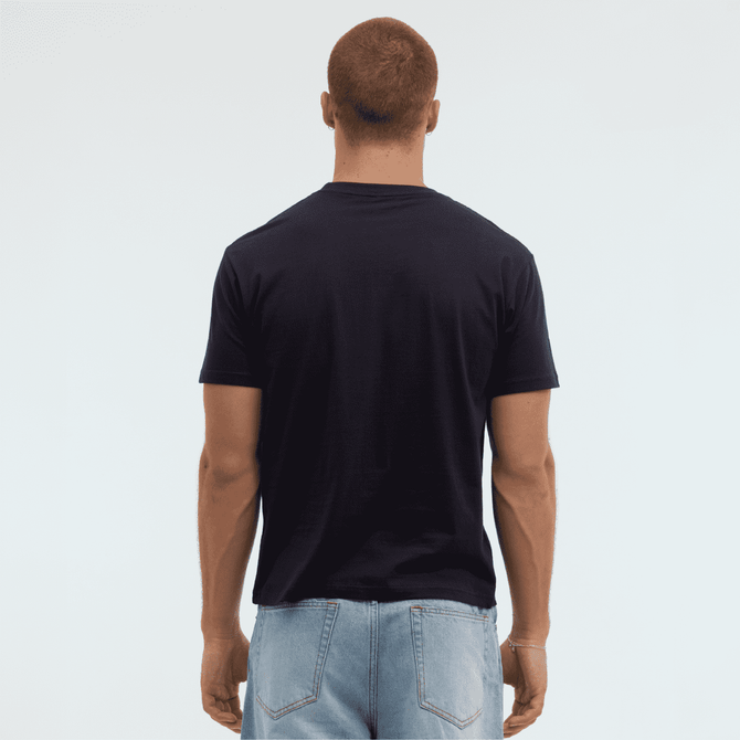 A navy Essential/Surf Tee displayed from the back on a model, wearing light blue jeans. The tee has a logo.
