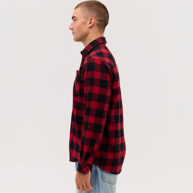 A long sleeve flannel shirt featuring a red and black check pattern, with a single chest pocket and a logo.