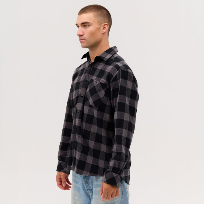 A long sleeve flannel shirt in black and grey check pattern, featuring a pocket and a logo.