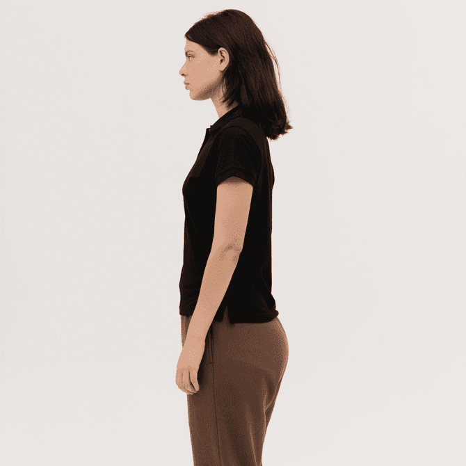 A black women's polo shirt is displayed on a model, shown in profile. The design includes short sleeves and a fitted shape.