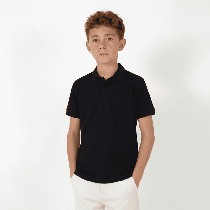 A youth polo shirt in black, featuring a collar and short sleeves, displayed on a model against a plain background.