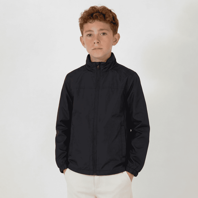 A youth jacket in navy blue with a zip front, featuring long sleeves and a high collar. It has a logo on one side.