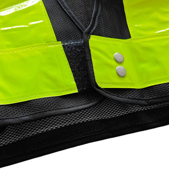 A reflective yellow safety vest with black mesh, featuring adjustable snaps and pockets. Includes a logo.