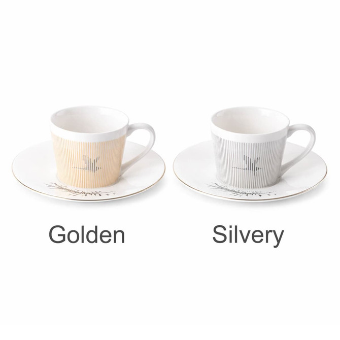 Two ceramic coffee mugs, one in golden and the other in silvery, each with matching saucers and a logo.