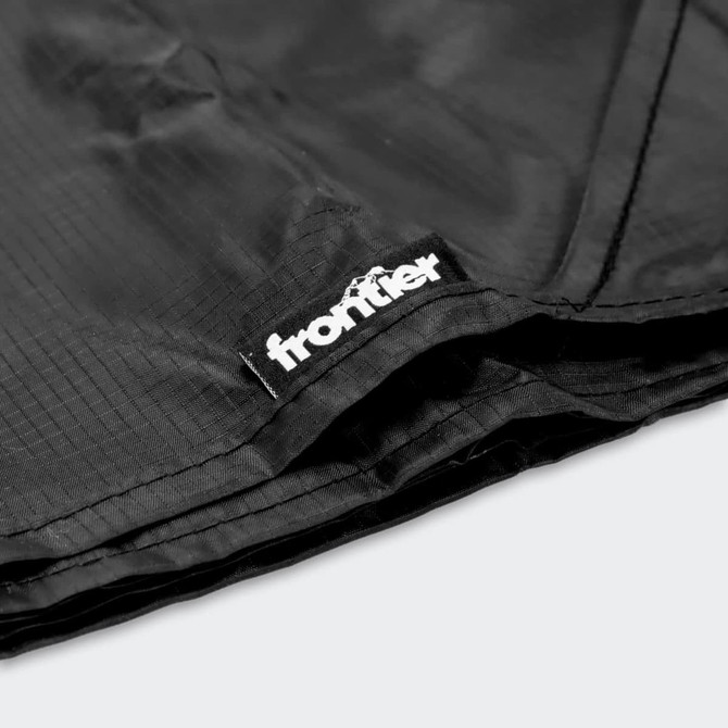 A black camping blanket with a logo tag, featuring textured fabric and a folded edge.