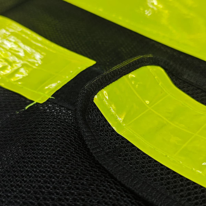 A close-up of a gourd-shaped hi-vis reflective adjustable safety vest in bright yellow and black mesh material, featuring a logo.