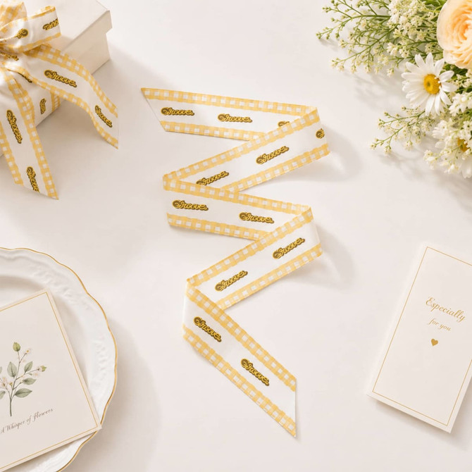 A satin narrow scarf featuring a white background with gold polka dots and a decorative edge, styled alongside floral arrangement.