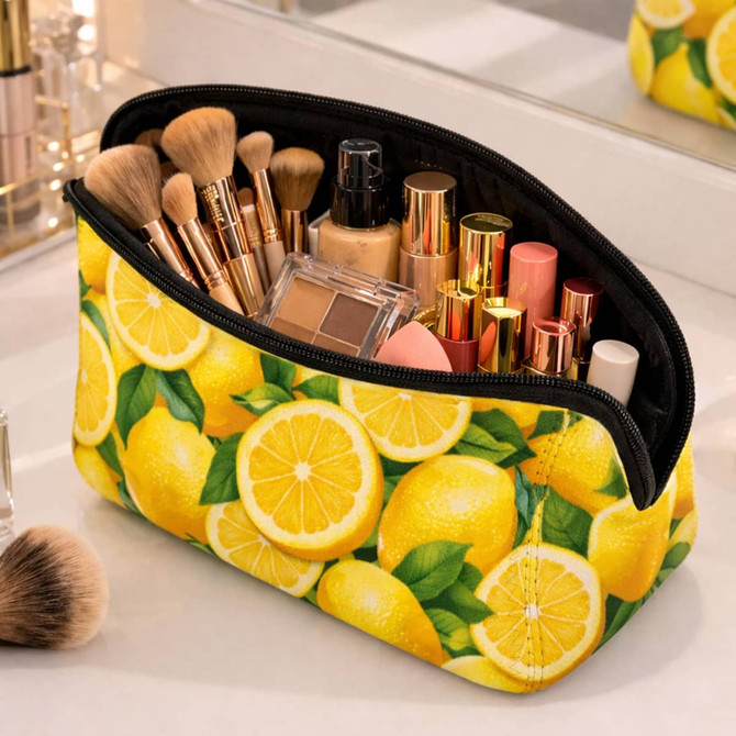 A yellow neoprene cosmetic bag filled with makeup brushes and various cosmetic products, featuring a lemon design.