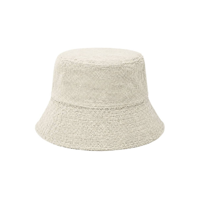 A dual-material reversible bucket hat in a light beige colour with a textured finish. It features a logo.