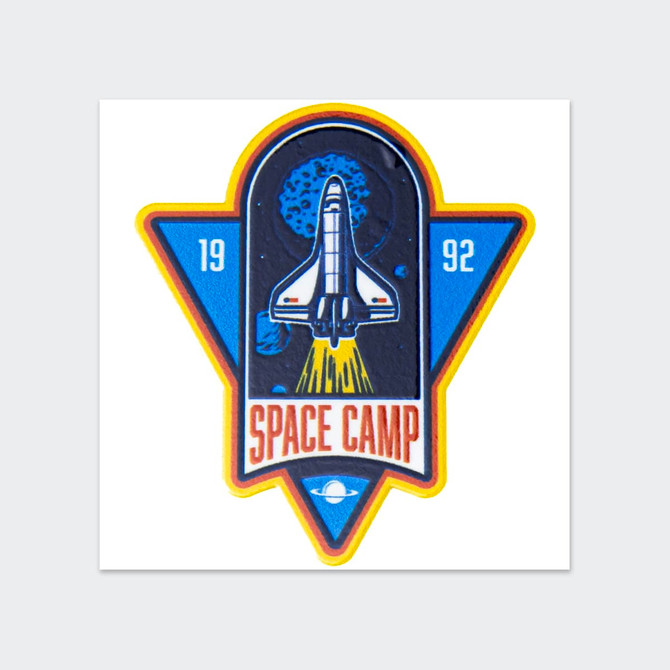 A vibrant sticker featuring a space shuttle launching, with blue and yellow elements, and an illustration of planets.