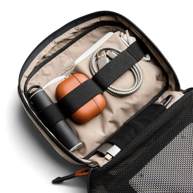 A tech kit featuring a grey exterior, tan interior, drink bottle, earphones, charging cables, and a pen.