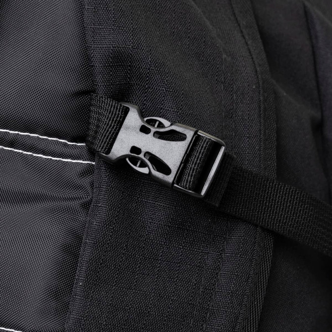 A close-up of a black backpack strap featuring a plastic buckle and stitched detailing.