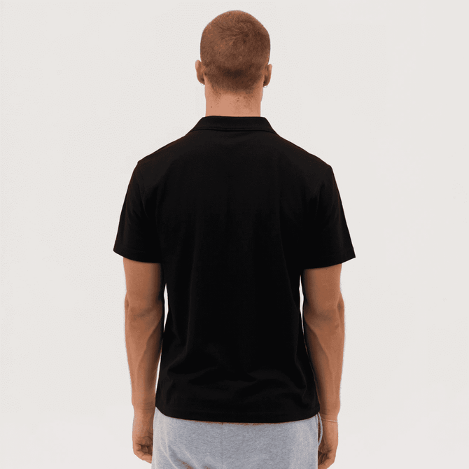 A black polo shirt viewed from the back, featuring a subtle logo on the collar.