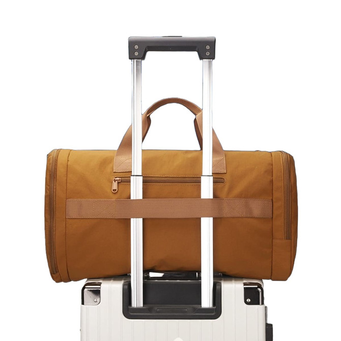 A foldable travel duffle bag in brown, sitting atop a wheeled suitcase with a retractable handle.