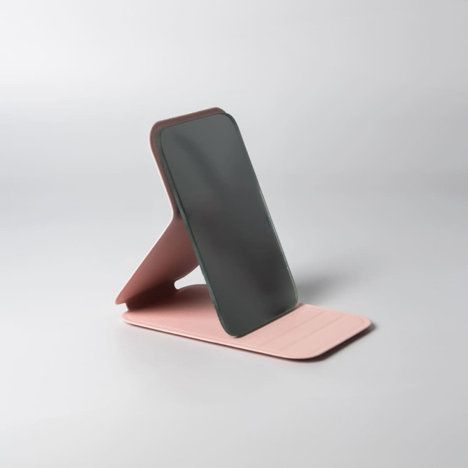 A compact pocket mirror with a stylish pink base and a dark reflective surface, featuring a design that allows for stand-up use.