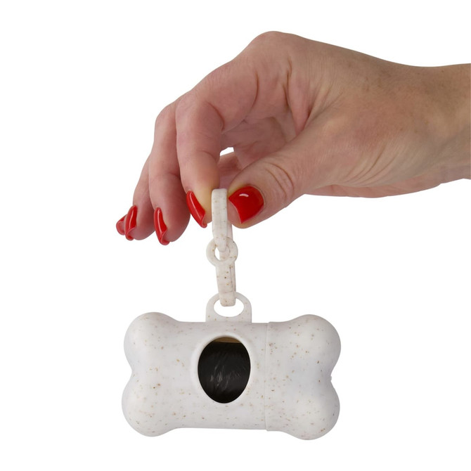 A bone-shaped dog waste bag dispenser in white, held by a hand with red nail polish. It features a clip for attachment.
