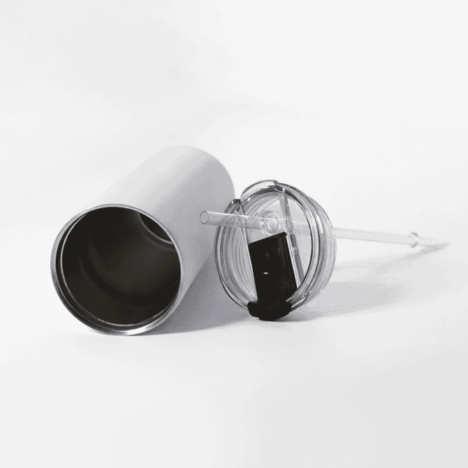 A drink bottle with a silver exterior, a clear lid, and a reusable straw lies on a white surface.