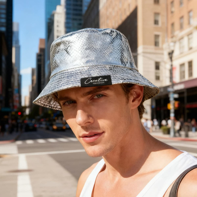 A silver glitter bucket hat, featuring a logo, worn by a model in an urban setting.