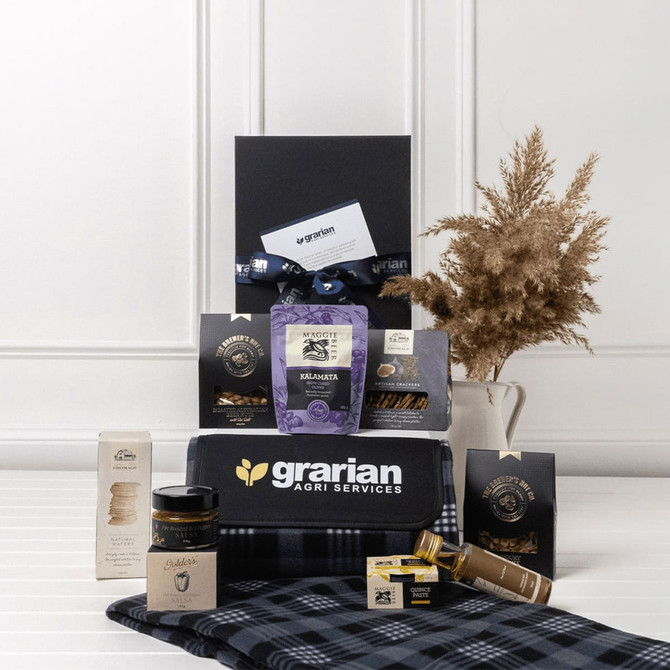 A picnic gift pack featuring a drink bottle, gourmet snacks, honey, and a checkered blanket in blue and black tones.