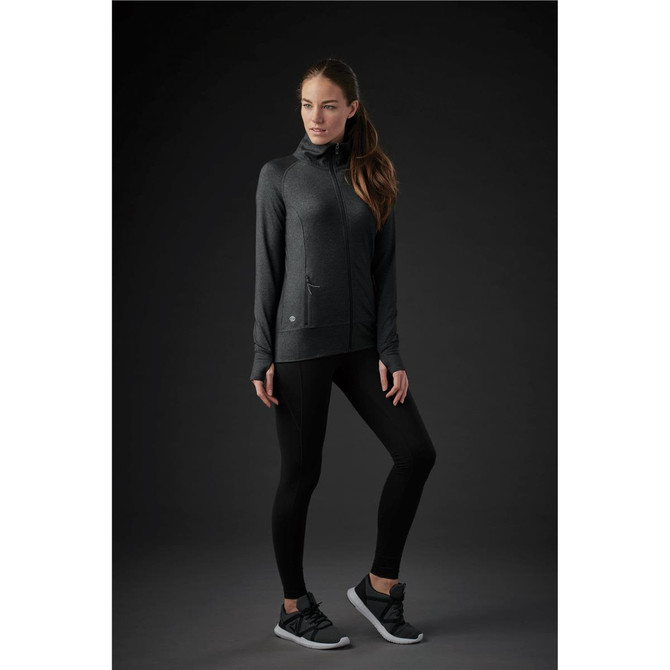 A long-sleeved women's jacket in dark grey with a zip-up front and a logo, paired with black leggings and shoes.