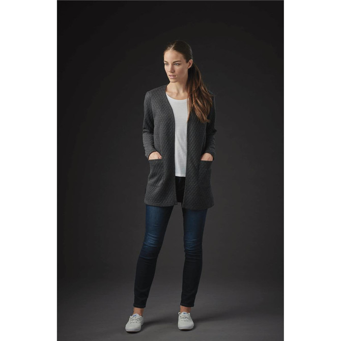 A woman wearing a dark grey Chelsea open cardigan over a white top, paired with dark jeans and casual white shoes.
