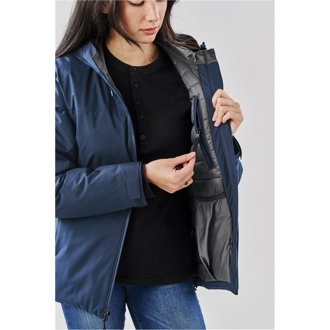 A woman wearing a navy lightweight shell jacket, showing the inside pocket. The jacket features a branding logo.
